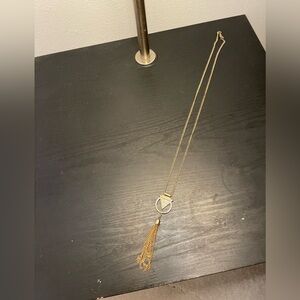 Long necklace with white triangle centerpiece and gold tassel bottom